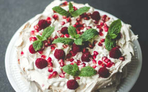 A pavlova with berries and mint.