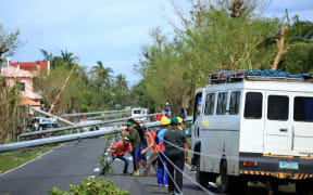 Workers check downed electric posts on the national road after typhoon Nock-Ten made landfall in Nabua, Camarines Sur.