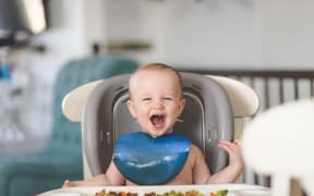Baby laughing in highchair