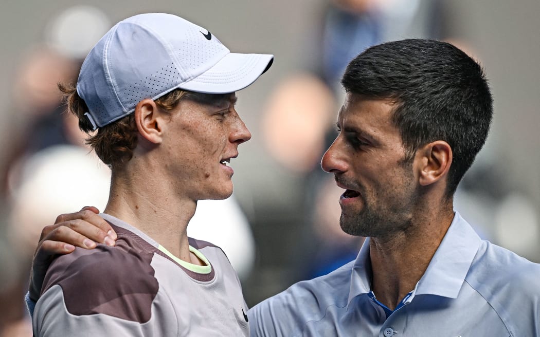Italy's Jannik Sinner greets Serbia's Novak Djokovic (R) after victory in their men's singles semi-final match on day 13 of the Australian Open tennis tournament in Melbourne on January 26, 2024. (Photo by Lillian SUWANRUMPHA / AFP) / -- IMAGE RESTRICTED TO EDITORIAL USE - STRICTLY NO COMMERCIAL USE --