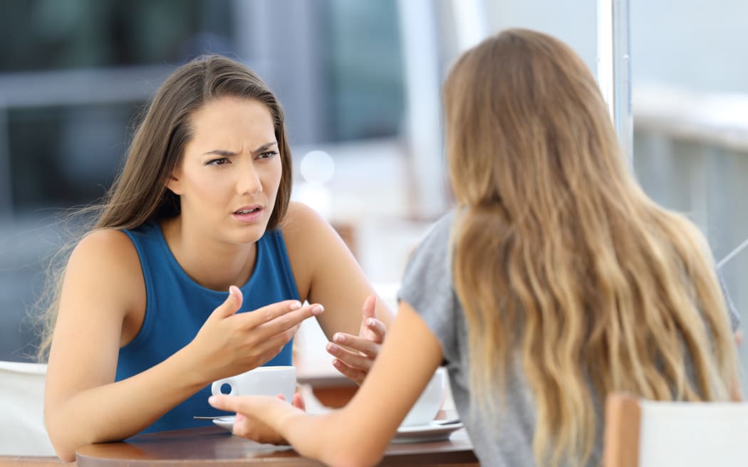 Two angry girls talking seriously sitting in a coffee shop
