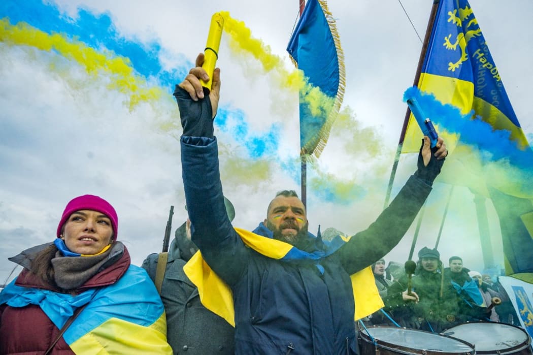 A man holds flares with the colors of the ukrainian flag in a nationalist march along the Paton bridge during the celebration of the Day of Unity in Kiev