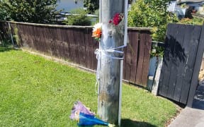 Flowers on Beach Haven Road in Auckland where a fatal incident took place.