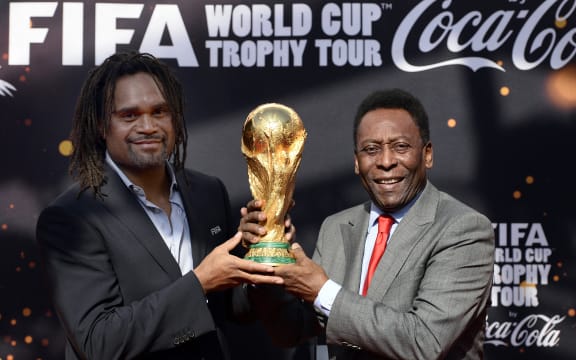 Brazilian football legend Pele (R) and former French international football player Christian Karembeu pose with the FIFA World Cup trophy during the FIFA World Cup Trophy Tour on March 9, 2014 outside the Hotel de Ville in Paris. The FIFA World Cup trophy arrived with its ambassador Pele in Paris on March 9, 2014 and will be exhibited on the Hotel de Ville plaza until March 10. This event kicks off the festivities of the FIFA World Cup 2014, that will be held in Brazil through June 12-July 13, 2014. AFP PHOTO / FRANCK FIFE (Photo by FRANCK FIFE / AFP)