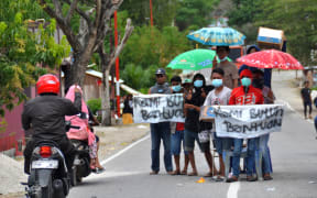 A group of villagers hold placards along a road near their destroyed village, asking for assistance in Palu, Indonesia's Central Sulawesi.