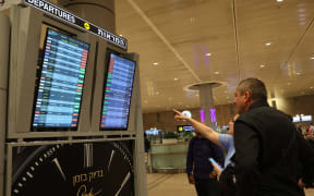 Passengers look at a departure board at Ben Gurion Airport near Tel Aviv, Israel, on October 7, 2023, as flights are canceled because of the Hamas surprise attacks. The conflict sparked major disruption at Tel Aviv airport, with American Airlines, Emirates, Lufthansa and Ryanair among carriers with cancelled flights.