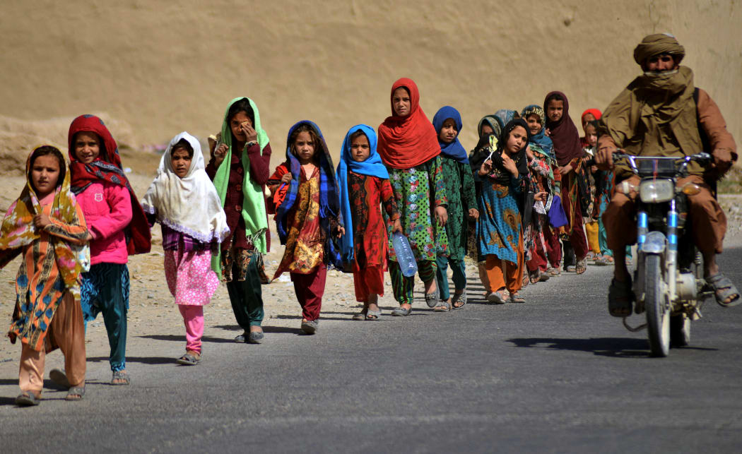 School children walk as they return to their homes after attending school along a roadside at Sperwan village in Panjwai district on October 24, 2021.