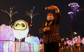 A woman takes a selfie in front of a display of Bing Dwen Dwen, the mascot of the 2022 Beijing Winter Olympics, at the Olympic Park in Beijing on January 18, 2022.