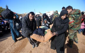 Syrian residents fleeing the violence gather at a checkpoint, manned by pro-government forces, in the village of Aziza on the southwestern outskirts of the northern Syrian city of Aleppo on December 8, 2016.