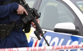 A police officer holds a gun at the scene of the shooting, which saw officers shoot a man dead.