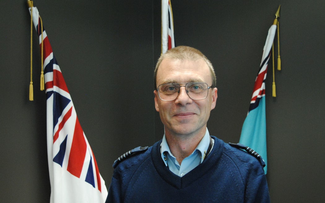 Portrait in front of flags leaning on wall behind