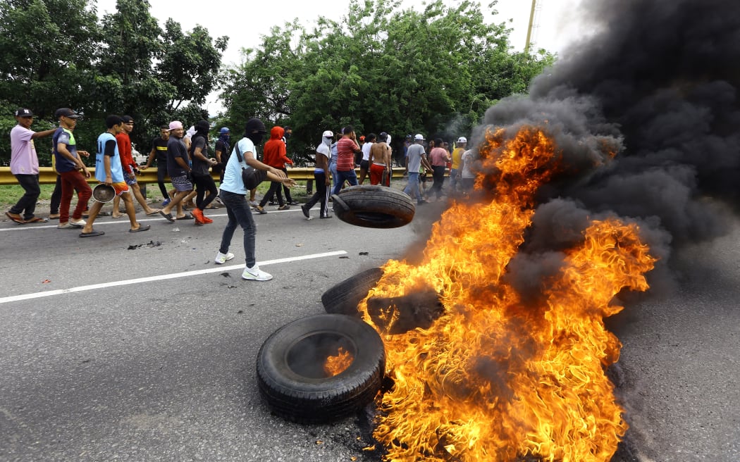 Opponents of Venezuelan President Nicolas Maduro's government burn tires during a protest in Valencia, state of Carabobo, Venezuela, on July 29, 2024, a day after the Venezuelan presidential election. Protests erupted in parts of Caracas Monday against the re-election victory claimed by Venezuelan President Nicolas Maduro but disputed by the opposition and questioned internationally, AFP journalists observed. (Photo by Juan Carlos HERNANDEZ / AFP)