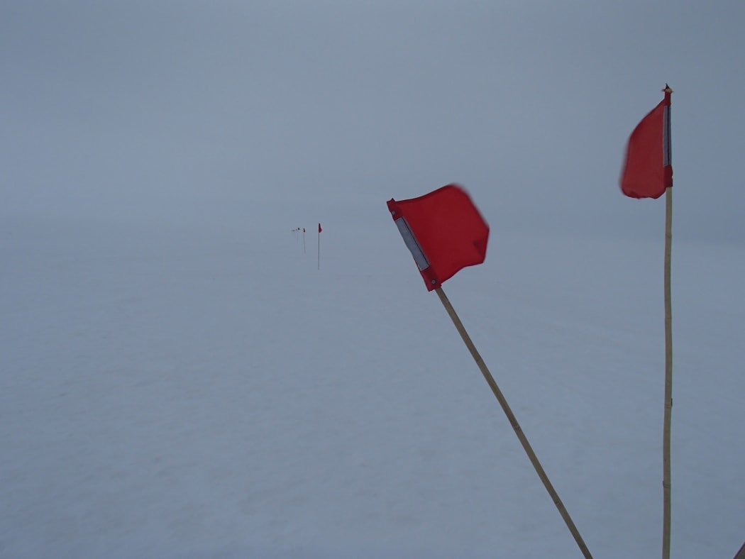 Small flags mark the safe route to walk during a white-out on the sea ice in front of Scott base, Antarctica.