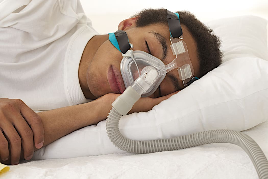 Young man sleeping with a CPAP machine
