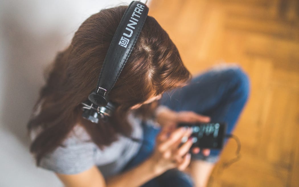 Woman listening via headphones and smartphone