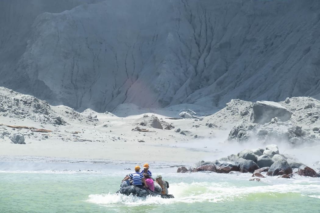 This handout photograph courtesy of Michael Schade shows White Island Tour operators rescuing people minutes after the volcano on New Zealand's White Island erupted on December 9, 2019.