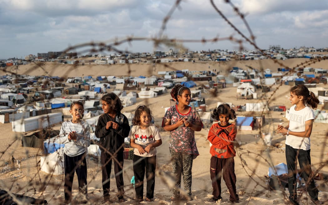 Children stand behind barbed wire along a slope near a camp housing displaced Palestinians in Rafah in the southern Gaza Strip on April 30, 2024, amid the ongoing conflict in the Palestinian territory between Israel and the militant group Hamas. (Photo by AFP)