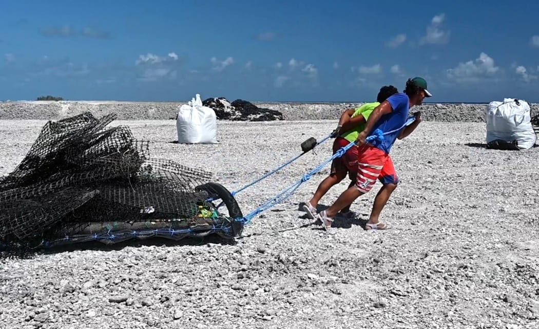 Support staff dragging rubbish in French Polynesia as part of a big clean-up from Pearl farms.