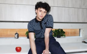Musical artist Luca George sits on a kitchen benchtop alongside an apple