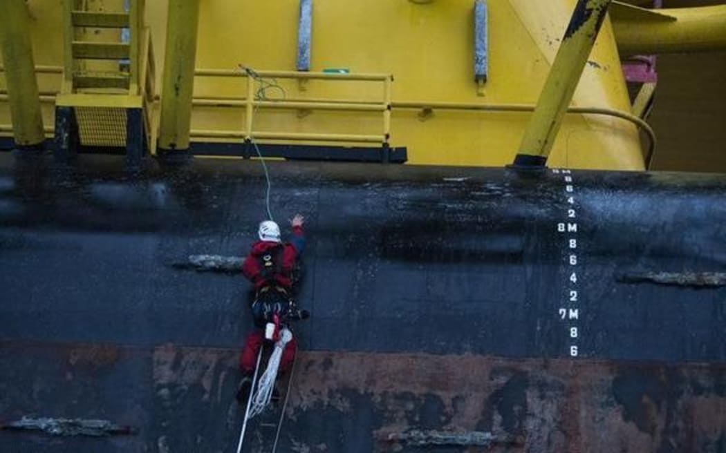 A Greenpeace activist scales the Polar Pioneer drill rig in the Pacific Ocean.