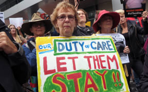 People hold up placards at a protest outside an immigration office in Sydney on February 4, 2016.