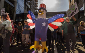 Protesters rally during the "No Kings" national day of protest in Minneapolis, Minnesota, on October 18, 2025. From New York to San Francisco, millions of Americans are expected to hit the streets to voice their anger over President Donald Trump's policies at nationwide "No Kings" protests. (Photo by Kerem YUCEL / AFP)