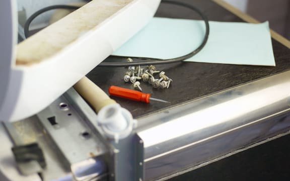 Small screws and screwdriver on a top of disassembled home appliance