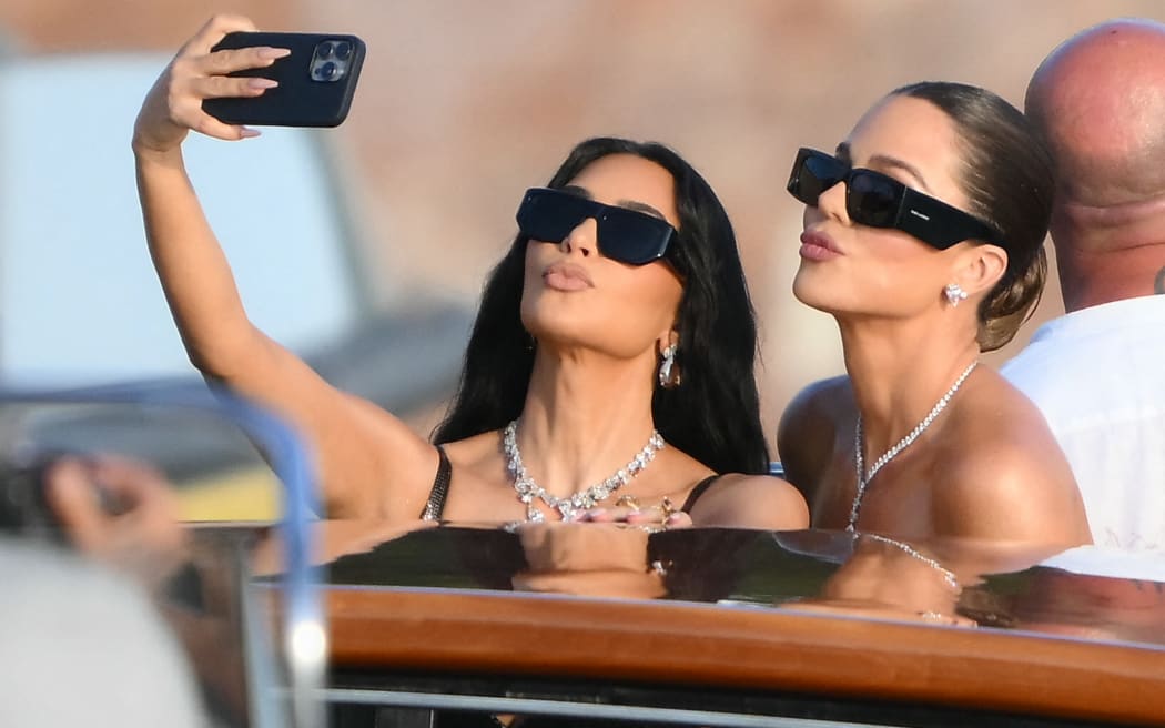 TOPSHOT - US reality TV personality Kim Kardashian (L) and US socialite Khloe Kardashian snap a selfie as they arrive at San Giorgio Maggiore on the wedding day of Amazon founder Jeff Bezos with Lauren Sanchez, in Venice on June 27, 2025.  (Photo by Marco BERTORELLO / AFP)
