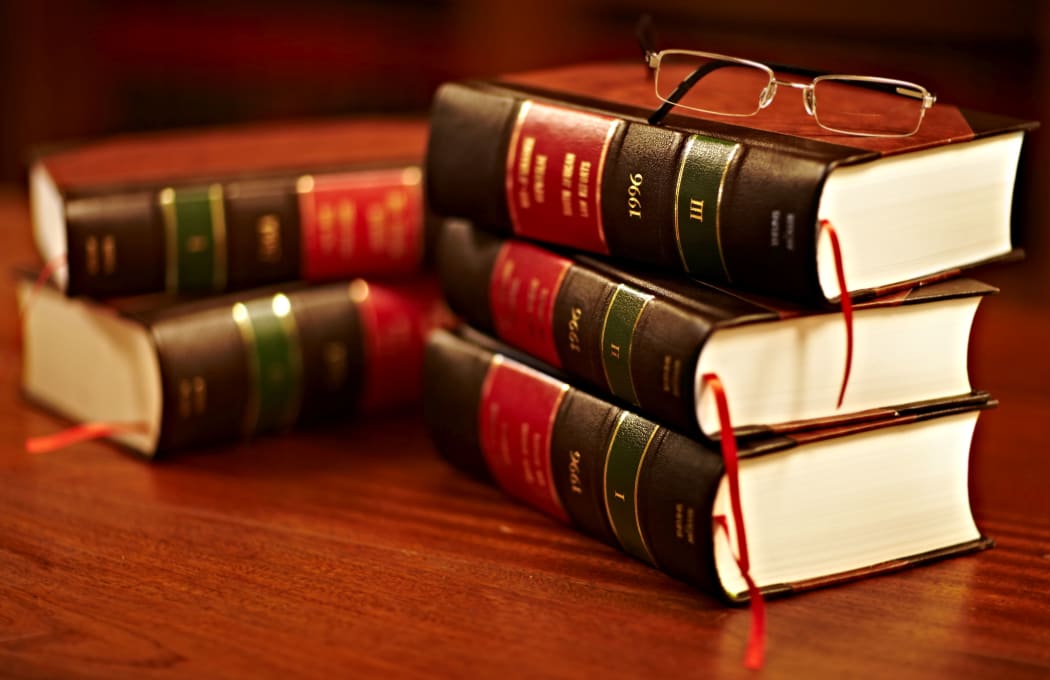 Shot of a stack of legal books and a pair of glasses on a table in a study.