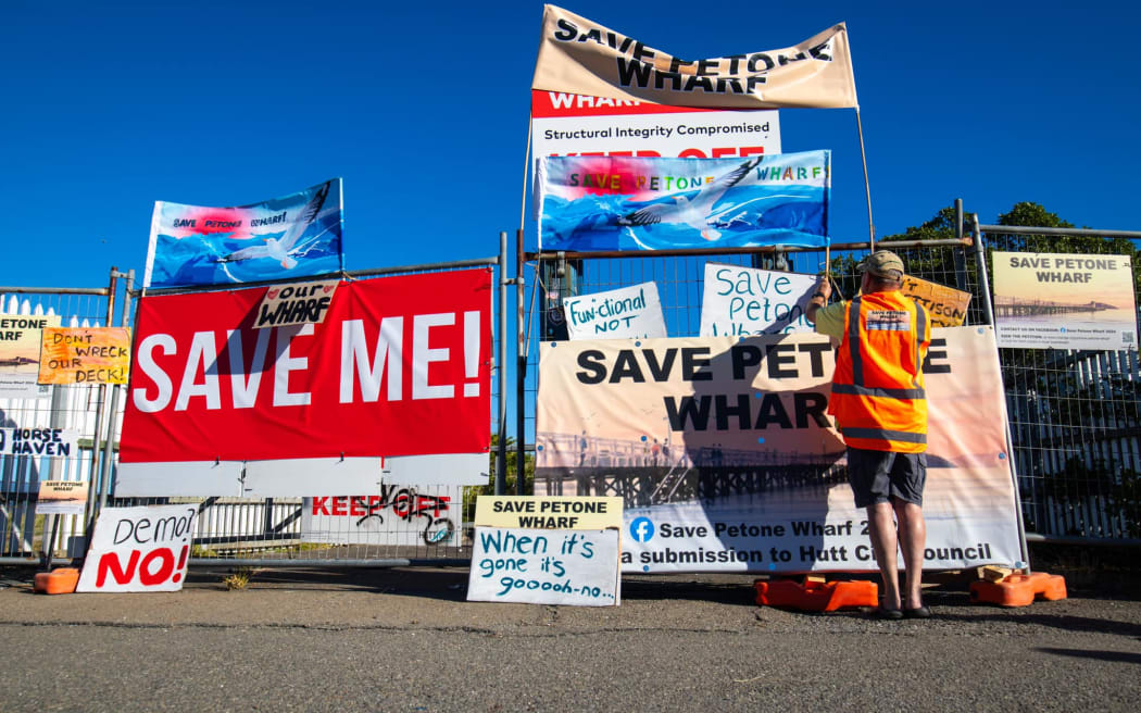 Some of the signs attached to the fenced-off Petone wharf, during a community walk to protest its planned demolition on 28 April 2024.