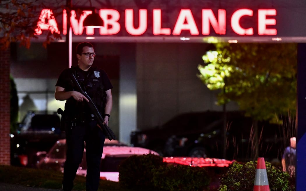 An armed police officer guards the ambulance entrance to the Central Maine Medical Center in Lewiston, Maine early on October 26, 2023 after a gunman killed at least 22 people and wounded dozens more. (Photo by Joseph Prezioso / AFP)