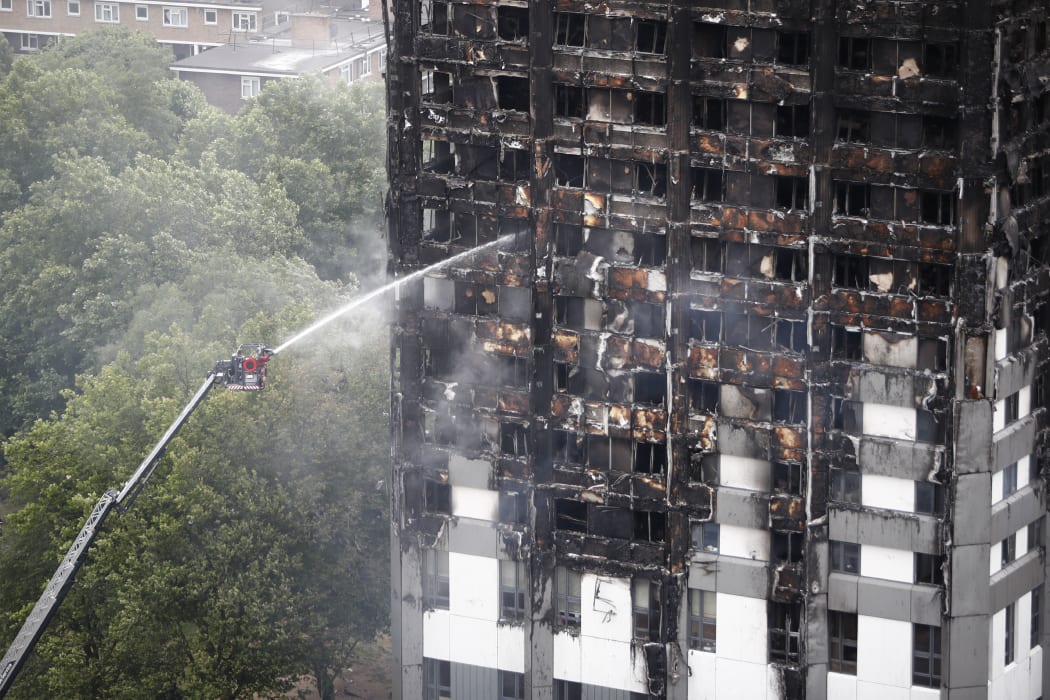 An automated hose sprays water onto Grenfell Tower.