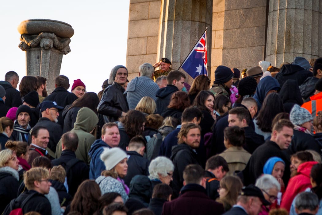 People line up to pay their respects as an elderly man salutes crowd during the Anzac dawn service in Melbourne.