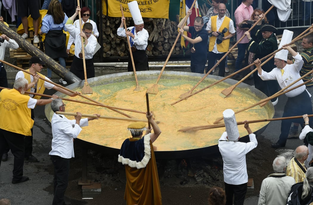 Members of a giant omelette fraternity create a 10,000-egg dish in a 4m-wide frying pan in the Belgian town of Malmedy on 15 August 2017.