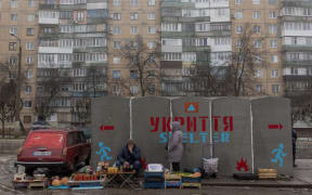 People sell vegetables and other goods next to a bomb shelter at a market in Kramatorsk, Donetsk region, on January 19, 2024, amid the Russian invasion of Ukraine. (Photo by Roman PILIPEY / AFP)