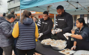 All Blacks Atu Moli (L) and Patrick Tuipolotu (R) serve sausages to fans.