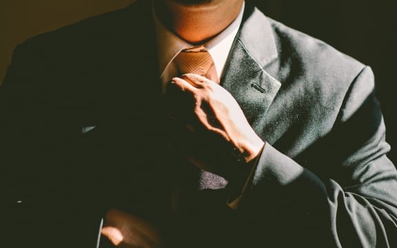 Man in suit adjusts tie