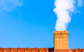 Modern house roof with chimney smoke, air pollution and smog in winter, ecological problems