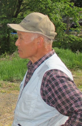 Farmer stands outside in cap and check shirt