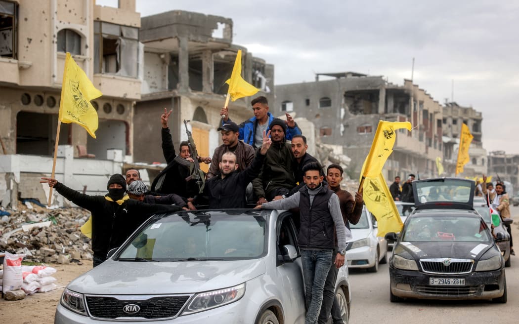 One of the Palestinian prisoners released in the fifth hostage-prisoner swap under the Gaza ceasefire deal gestures as he stands through the sunroof of a vehicle while others around him wave flags of the Palestinian Fatah movement, on their way to the European Hospital in Khan Yunis in the southern Gaza Strip on February 8, 2025. Hamas militants handed over three Israeli hostages on February 8, as part of the fifth exchange under a fragile Gaza ceasefire, with 183 prisoners held by Israel due to be released later in the day. (Photo by Eyad BABA / AFP)