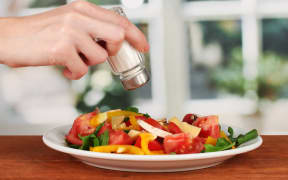 16738591 - hand adding salt using  salt shaker on bright background