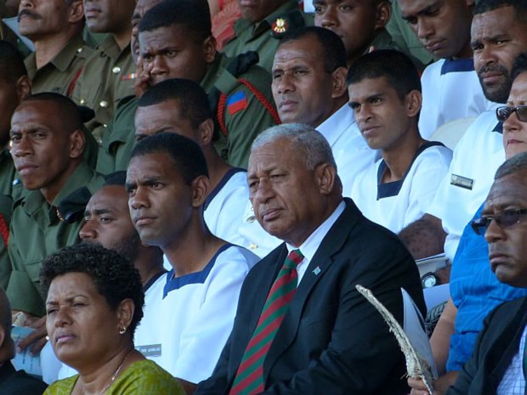 Fiji's Prime Minister, Frank Bainimarama, sitts among soliders at thanksgiving service for release of UN peacekeepers.