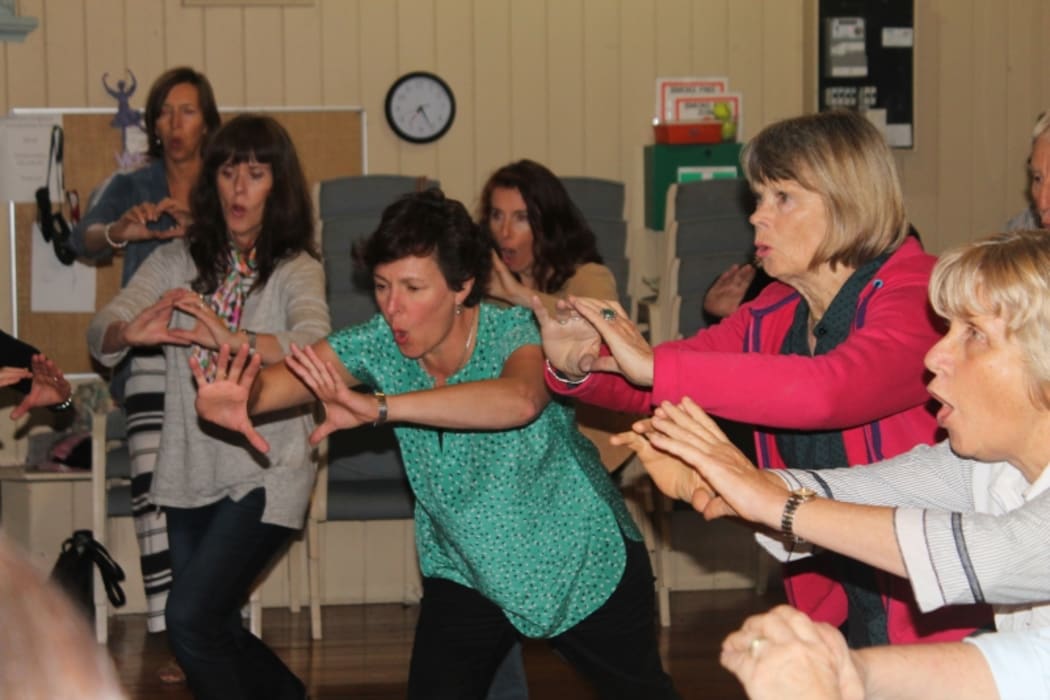 A photo of the choir members warming up by vocalising, shaking and moving.