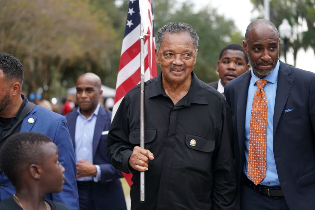 Rev. Jesse Jackson carries an American flag outside the Glynn County Courthouse, where three white men are on trial for the murder of Ahmaud Arbery.