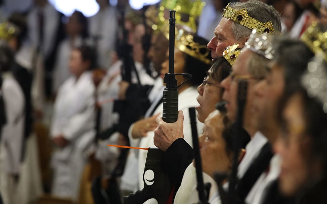 NEWFOUNDLAND, PA - FEBRUARY 28: Couples hold AR-15 rifles and other guns during a ceremony at the World Peace and Unification Sanctuary on February 28, 2018 in Newfoundland, Pennsylvania. The controversial church, which is led by the son of the late Rev. Sun Myung Moon, believes the AR-15 symbolizes the "rod of iron" in the biblical book of Revelation, and it has encouraged couples to bring the weapons to a "commitment ceremony" or "Perfection Stage Book of Life Registration Blessing". Officials in the rural area in the Pocono Mountains have reportedly told elementary school parents that their children will be relocated on Wednesday to accommodate the AR-15 ceremony. The semiautomatic rifles are similar to the weapon used in a Florida high school shooting on February 14.   Spencer Platt/Getty Images/AFP (Photo by SPENCER PLATT / GETTY IMAGES NORTH AMERICA / Getty Images via AFP)