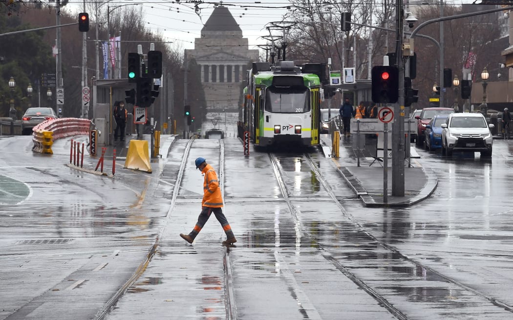 A worker crosses the street in Melbourne's central business district on August 19, 2020, as the city battles an outbreak of the COVID-19 coronavirus. -