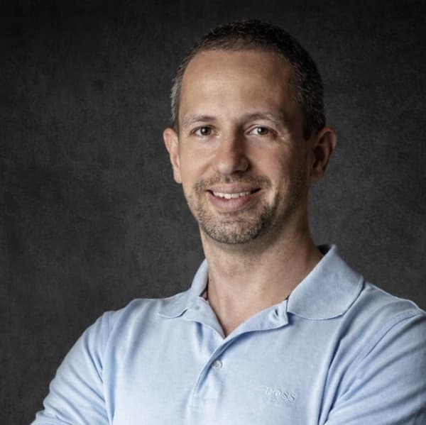 Kirill Ilin vis a smiling bearded man in a pale blue polo shirt.