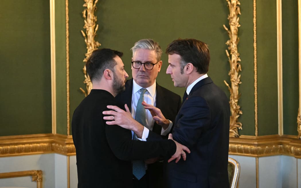 (L-R) Ukraine's President Volodymyr Zelensky, Britain's Prime Minister Keir Starmer and France's President Emmanuel Macron embrace after holding a meeting during a summit at Lancaster House in central London on March 2, 2025. European leaders descend upon London today for talks to "drive forward" action on Ukraine, according to the office of UK Prime Minister Keir Starmer. The summit caps off a week of intense diplomacy for host Starmer, who met with President Donald Trump on Thursday in an effort to draw together the European and US approaches to the Ukraine conflict.