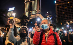 People hold their mobile phones as they gather to pray for the students who are barricaded inside Hong Kong Polytechnic University.