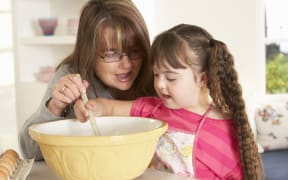 A photo of a girl with downs syndrome baking with mother